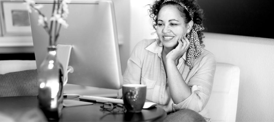 woman sitting at table in front of computer smiling